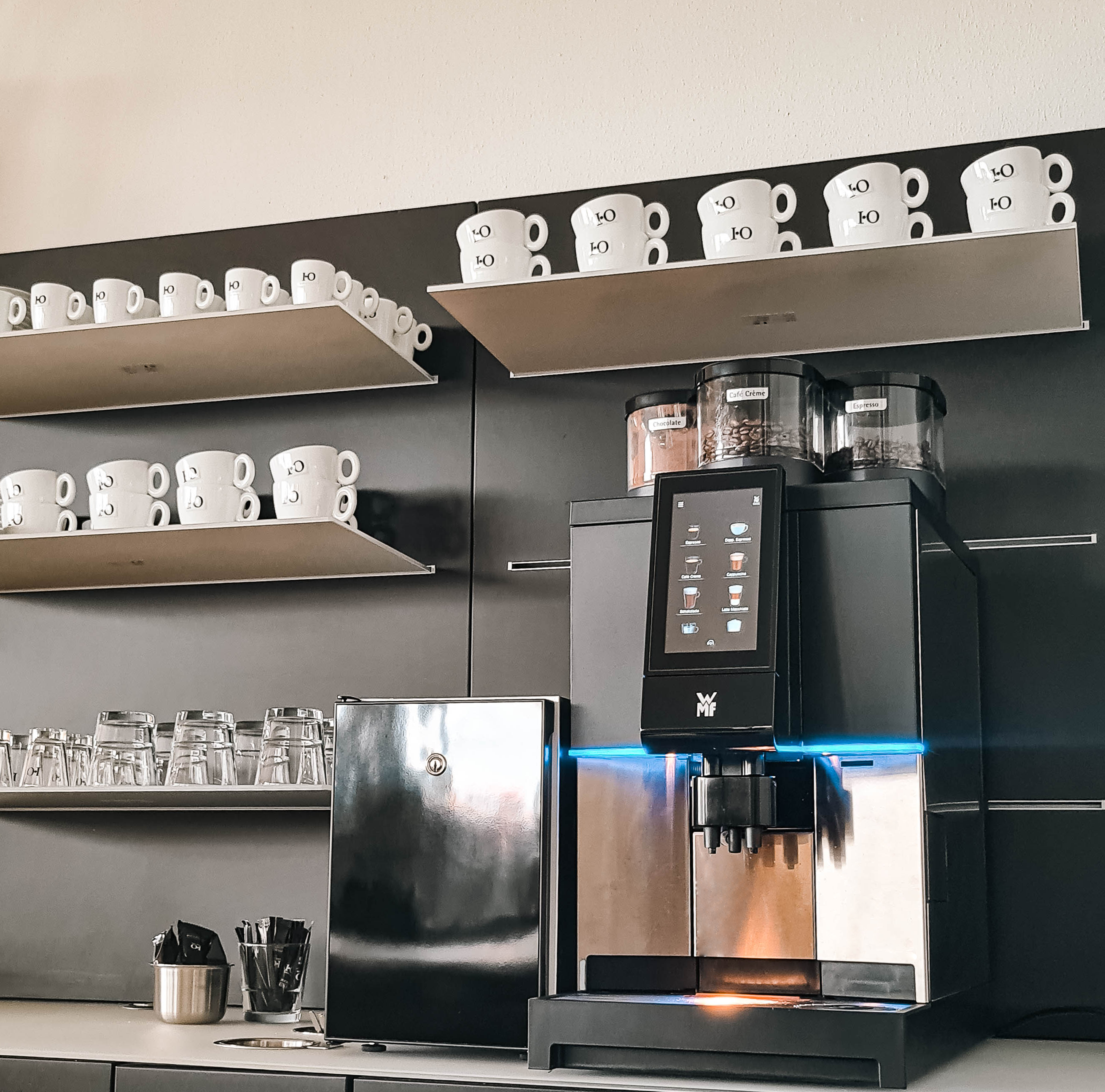 Kaffeemaschine auf Tresen mit Tassen im Hintergrund